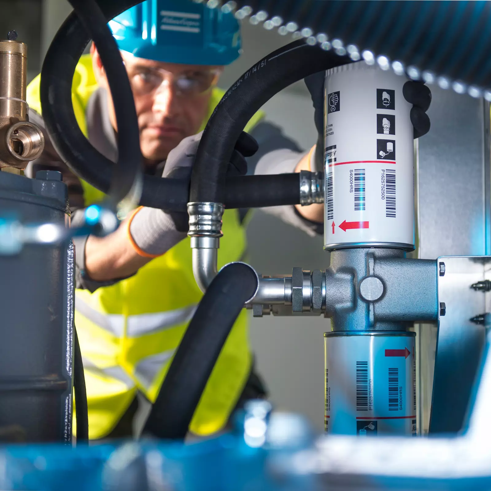 Engineer fitting a spin-on oil filter to a compressor