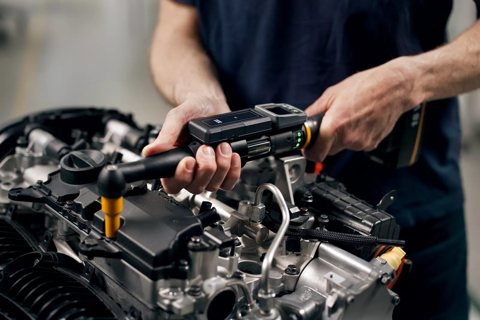 Assembly worker tightening an engine fastener with an electronic torque wrench