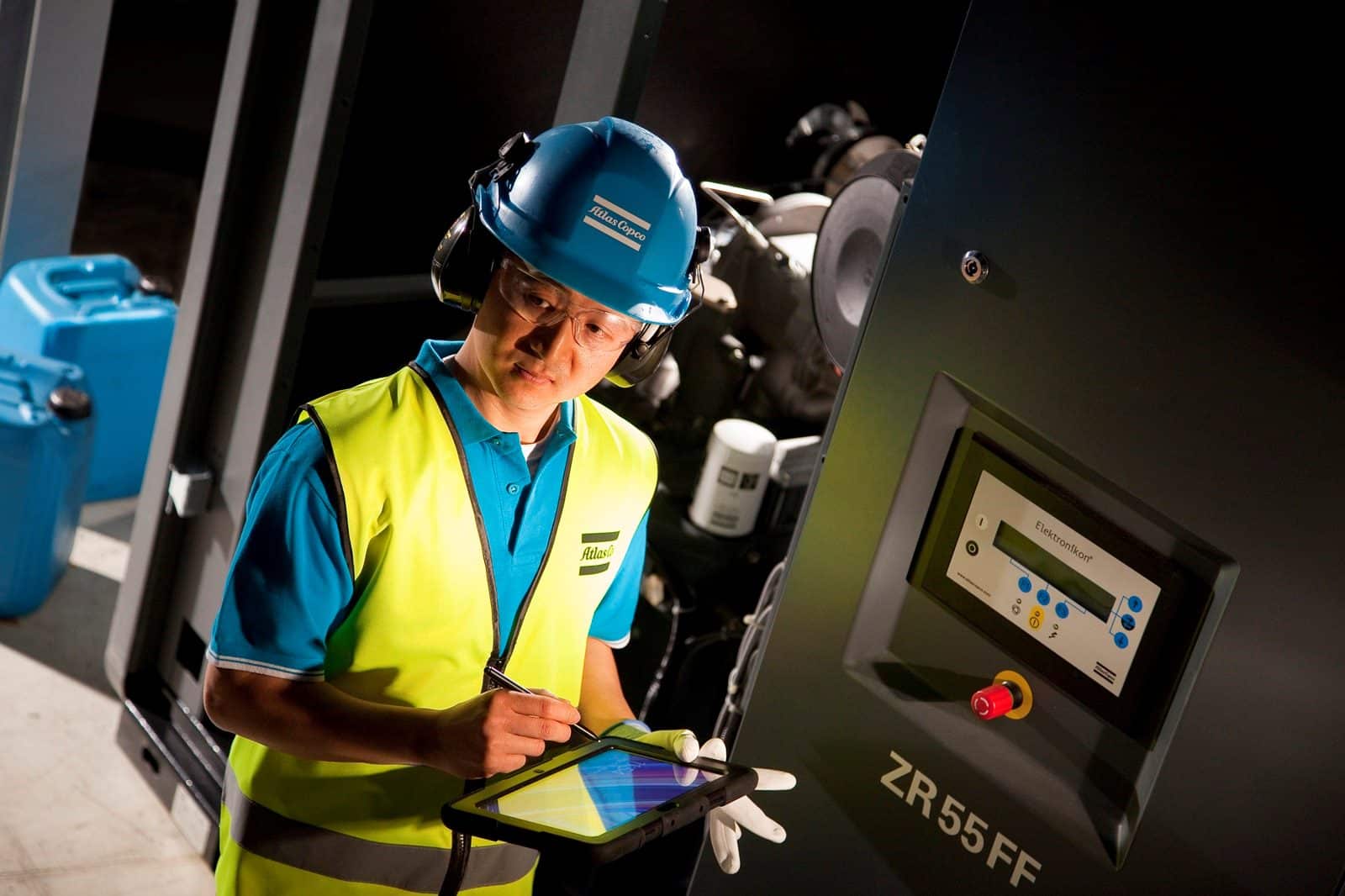 Engineer with a tablet checking an Atlas Copco ZR oil-free compressor