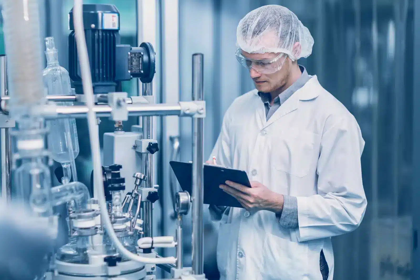 Technician recording checks on pharmaceutical process equipment