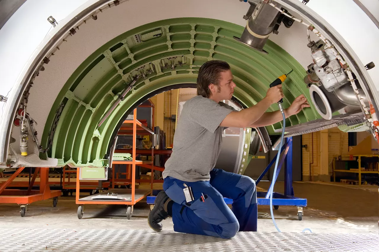 Technician drilling inside an aircraft fuselage section with an air tool