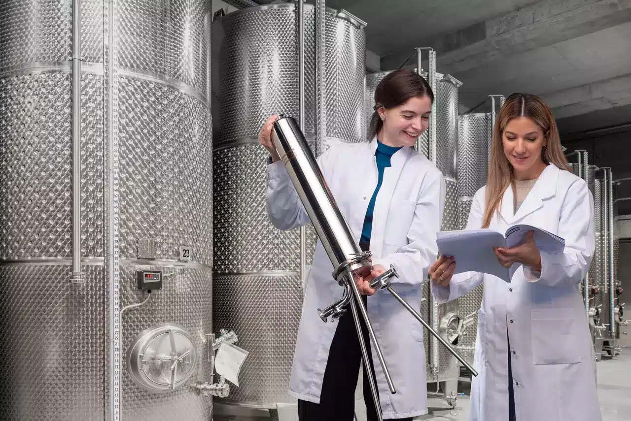 Quality staff sampling beside stainless steel process tanks