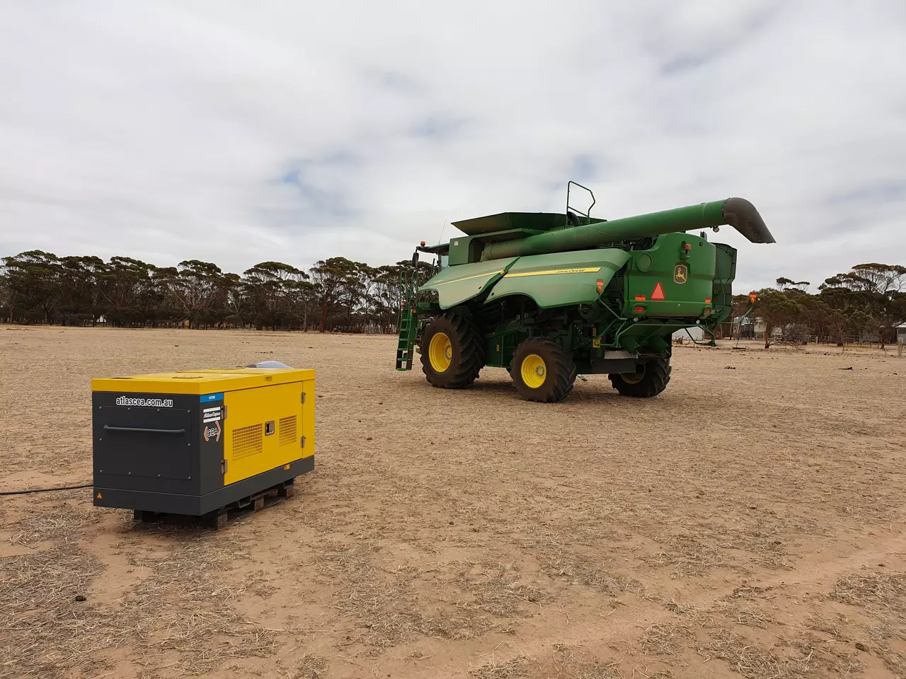 Combine harvester and a portable Atlas Copco compressor on a farm